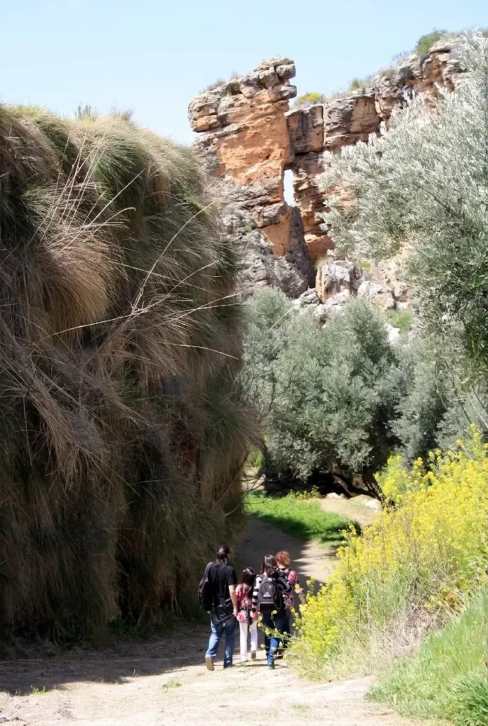 Grupo de amigos realizando una ruta de senderismo junto a las formaciones del Balneario de Alicún de las Torres. Actividad recomendada a los huéspedes alojados en la casa cueva Alhama en Graena.