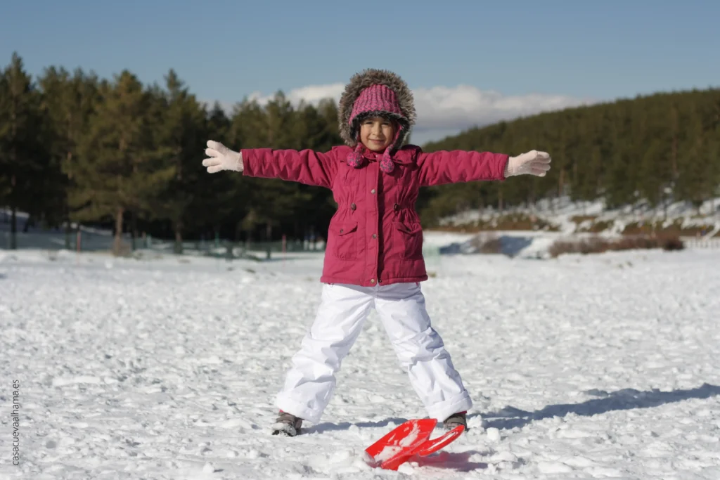 Niña disfrutando de la nieve con trineo en el Puerto de la Ragua en el Parque NAcional de Sierra Nevada, actividad familiar recomendada a unpaso de la cueva turística Casa Cueva Alhama en Graena, Granada